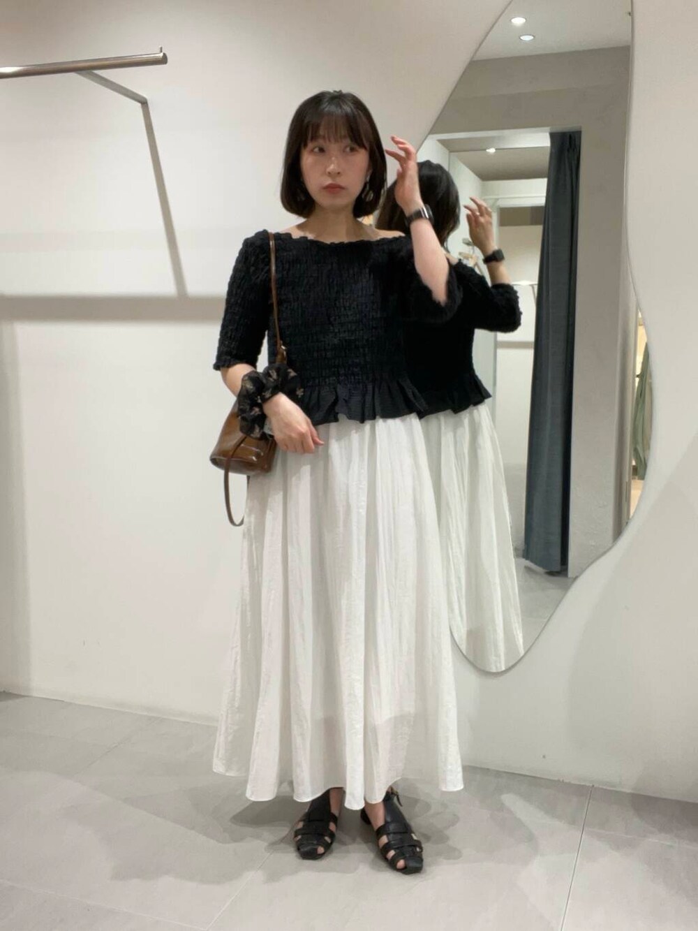 ブラウン系のショルダーバッグ、ホワイト系のスカート、ブラック系のシャツ/ブラウスを着用したレディースの春コーディネートの4枚目の写真