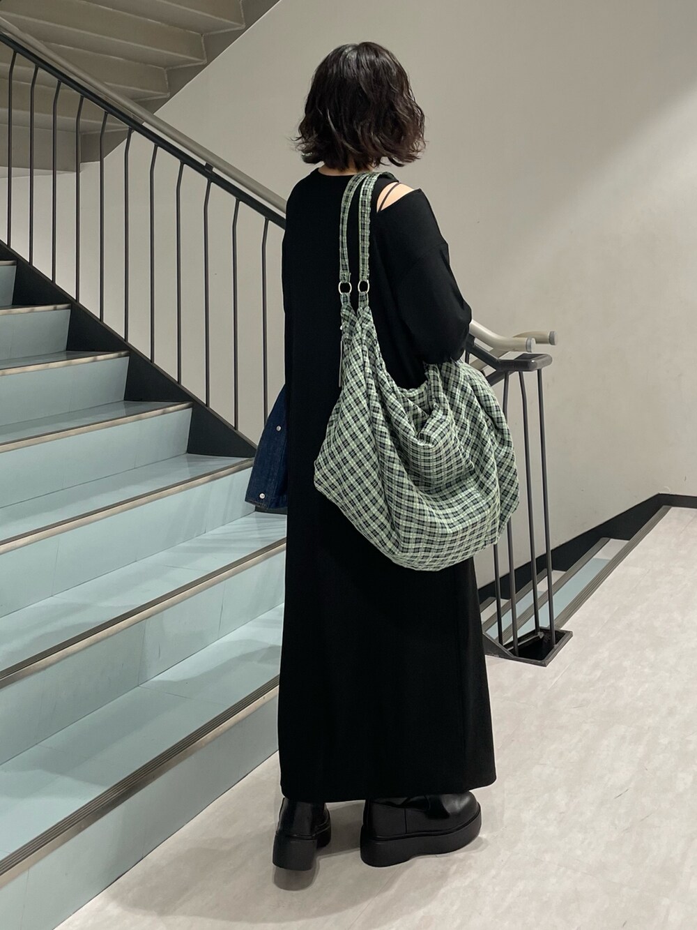 ブルー系のブルゾン、ブラック系のワンピース、ブラック系のブーツを着用したレディースの秋コーディネートの4枚目の写真