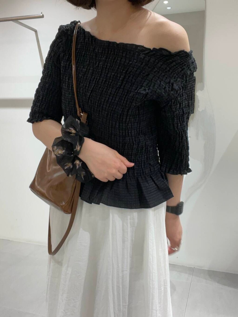 ブラウン系のショルダーバッグ、ホワイト系のスカート、ブラック系のシャツ/ブラウスを着用したレディースの春コーディネートの3枚目の写真