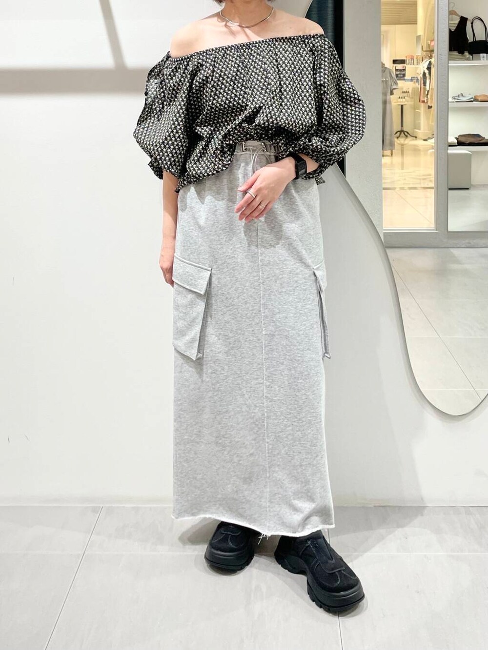 ブラック系のシャツ/ブラウス、グレー系のスカート、ブラック系のスニーカーを着用したレディースの夏コーディネートの4枚目の写真