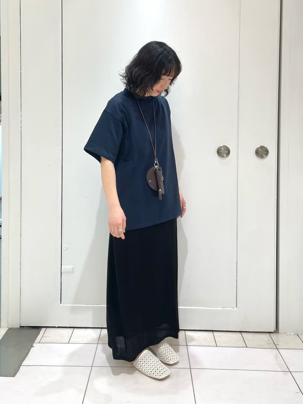 ブラック系のスカート、ブルー系のTシャツ/カットソー、ホワイト系のサンダルを着用したレディースの冬コーディネートの2枚目の写真