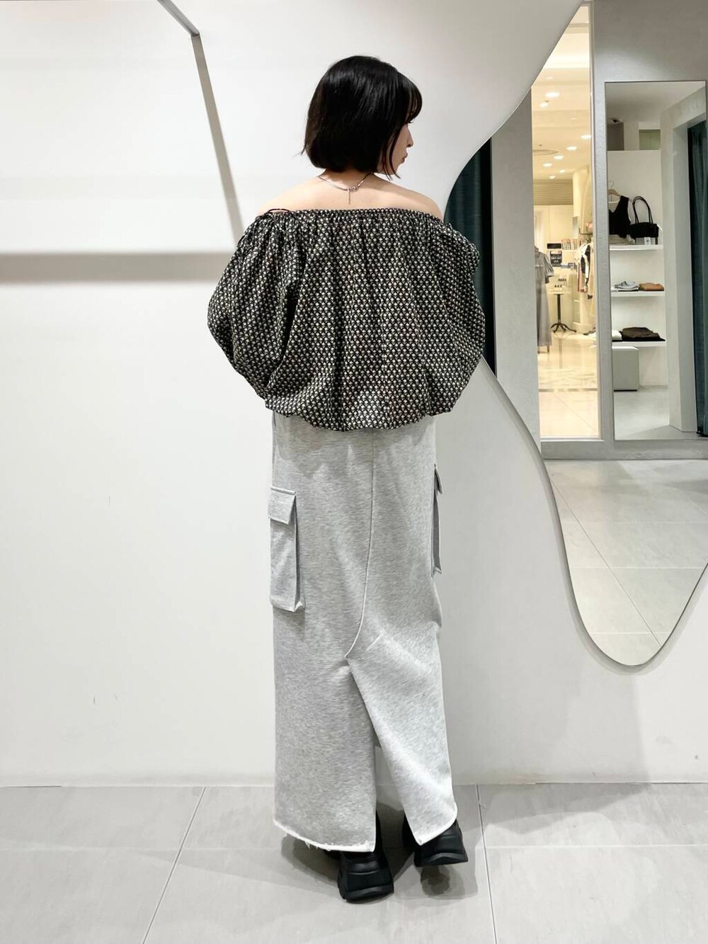 ブラック系のシャツ/ブラウス、グレー系のスカート、ブラック系のスニーカーを着用したレディースの夏コーディネートの2枚目の写真