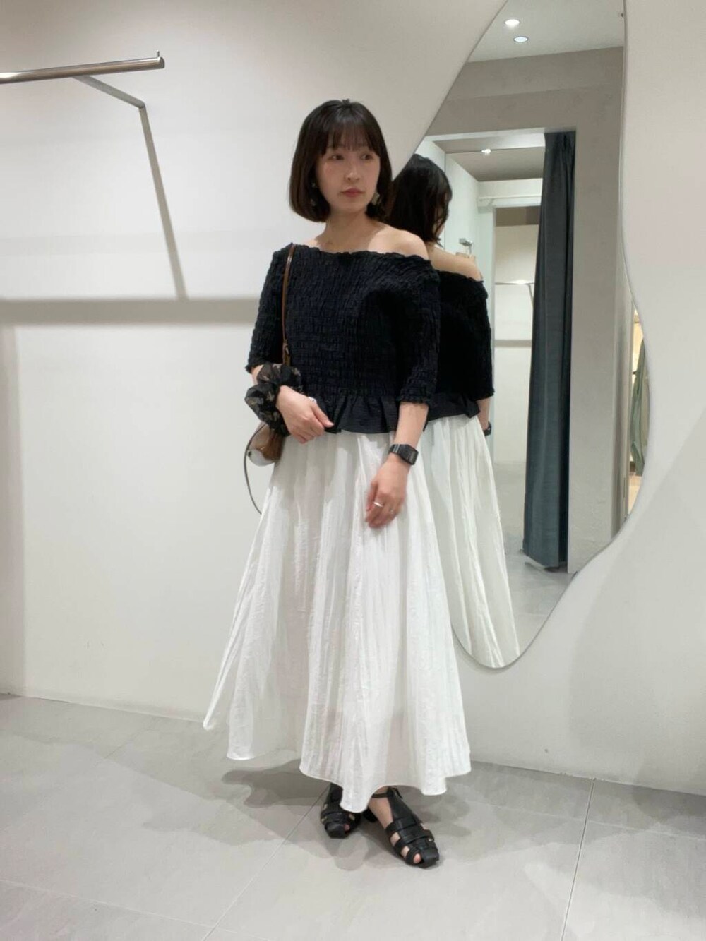 ブラウン系のショルダーバッグ、ホワイト系のスカート、ブラック系のシャツ/ブラウスを着用したレディースの春コーディネートの5枚目の写真