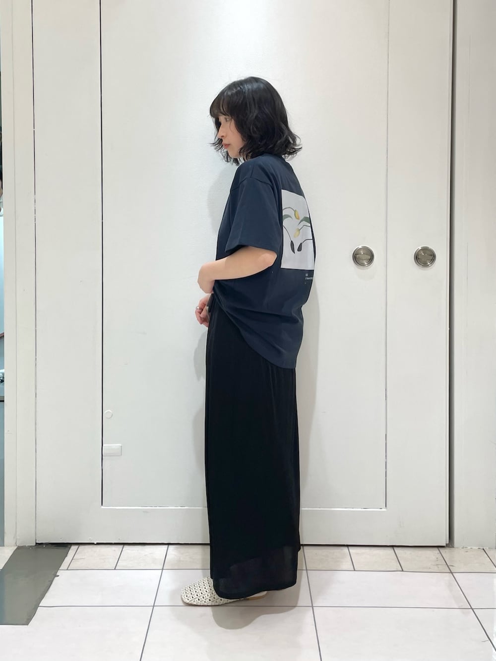 ブラック系のスカート、ブルー系のTシャツ/カットソー、ホワイト系のサンダルを着用したレディースの冬コーディネートの3枚目の写真