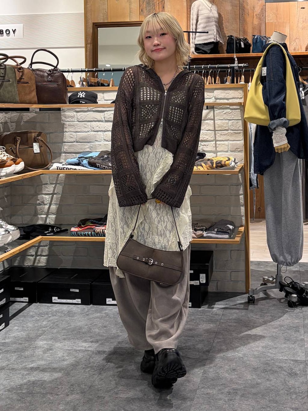 ブラック系のブーツ、ブラウン系のハンドバッグ、ホワイト系のチュニックを着用したレディースの春コーディネートの6枚目の写真