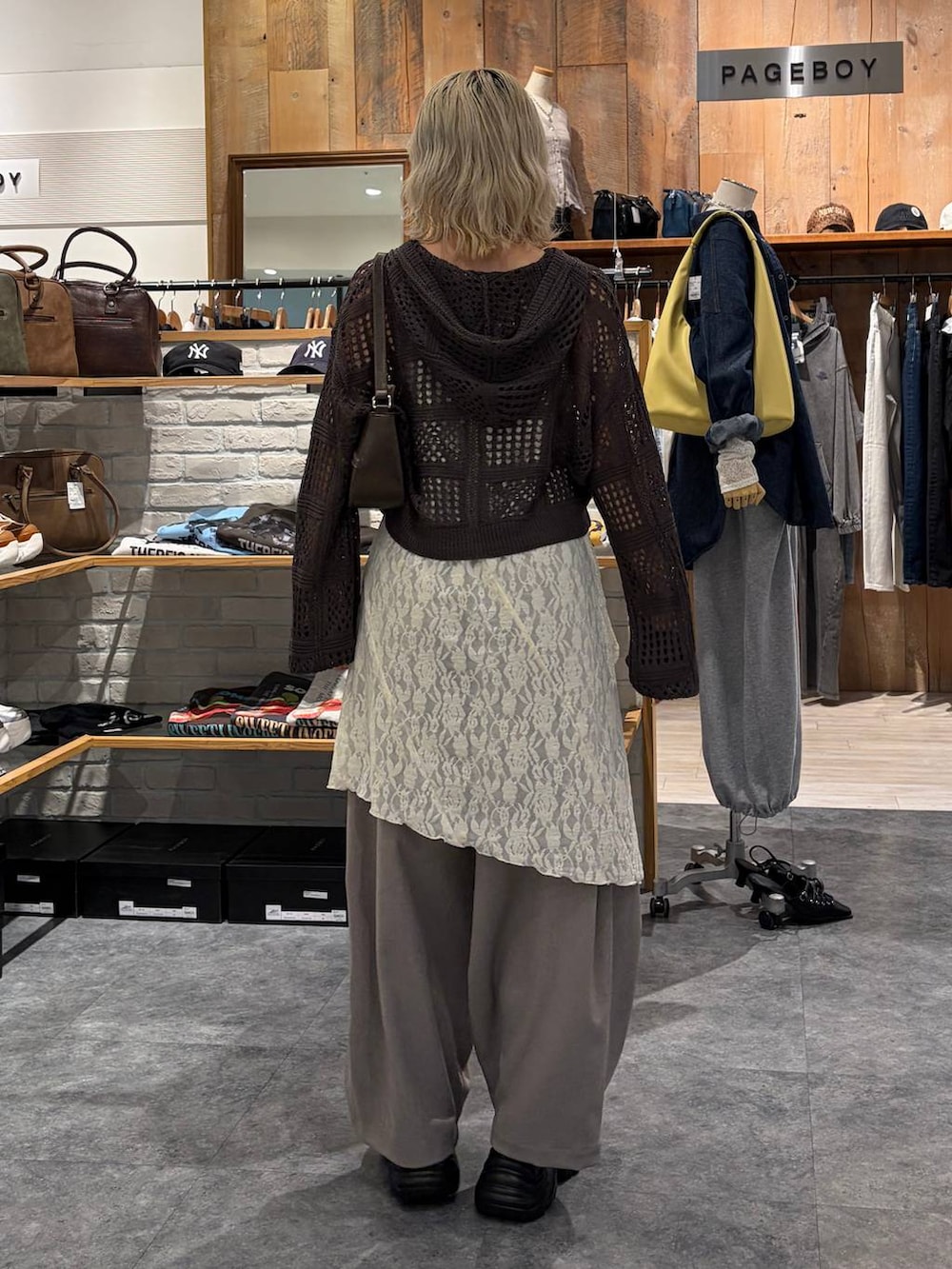 ブラック系のブーツ、ブラウン系のハンドバッグ、ホワイト系のチュニックを着用したレディースの春コーディネートの4枚目の写真