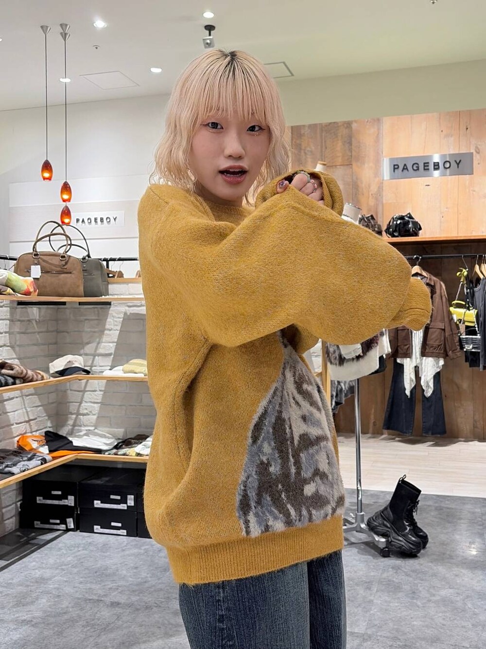 イエロー系のニット/セーター、ブルー系のデニムパンツを着用したレディースの秋コーディネートの4枚目の写真