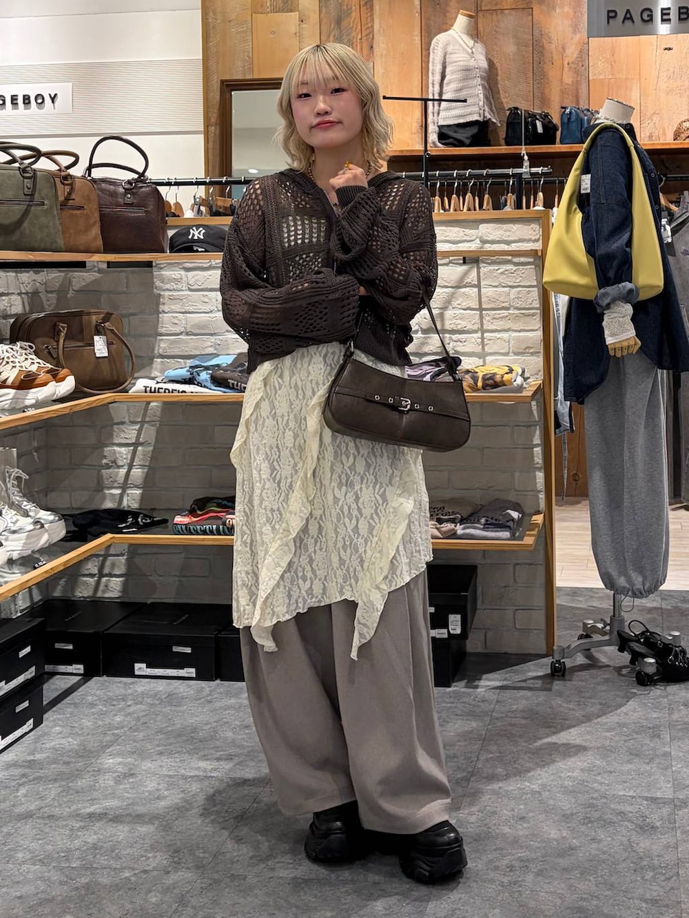 ブラック系のブーツ、ブラウン系のハンドバッグ、ホワイト系のチュニックを着用したレディースの春コーディネートの2枚目の写真