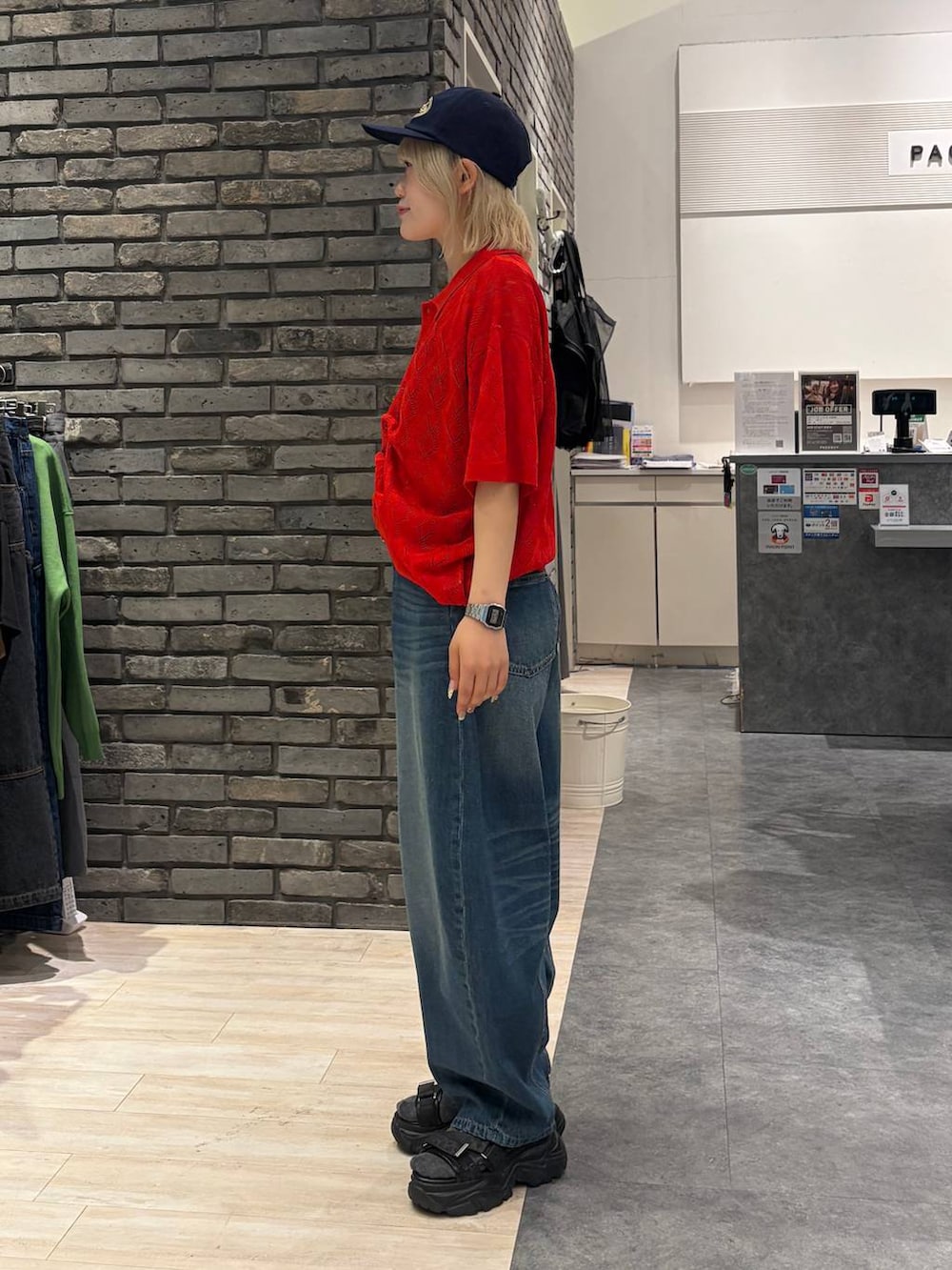レッド系のポロシャツ、ブラック系のサンダル、ブルー系のデニムパンツを着用したレディースの夏コーディネートの5枚目の写真