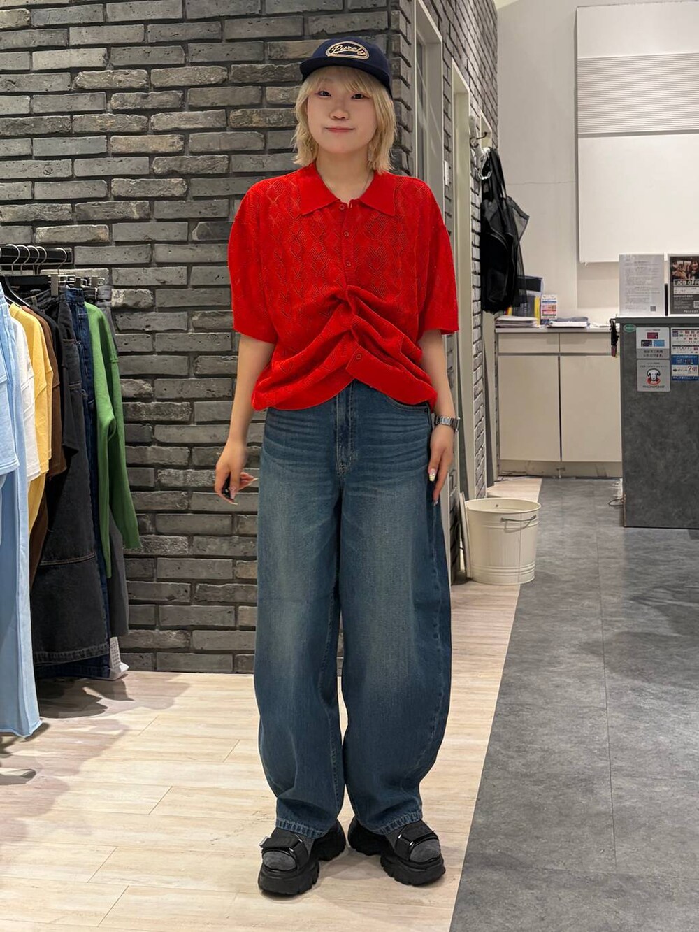 レッド系のポロシャツ、ブラック系のサンダル、ブルー系のデニムパンツを着用したレディースの夏コーディネートの6枚目の写真