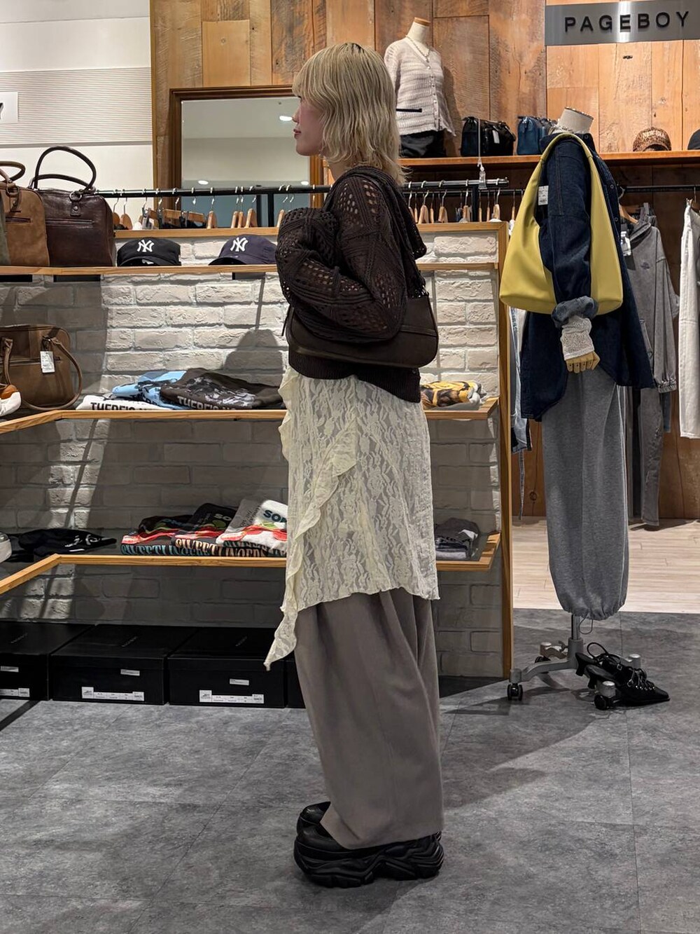 ブラック系のブーツ、ブラウン系のハンドバッグ、ホワイト系のチュニックを着用したレディースの春コーディネートの5枚目の写真