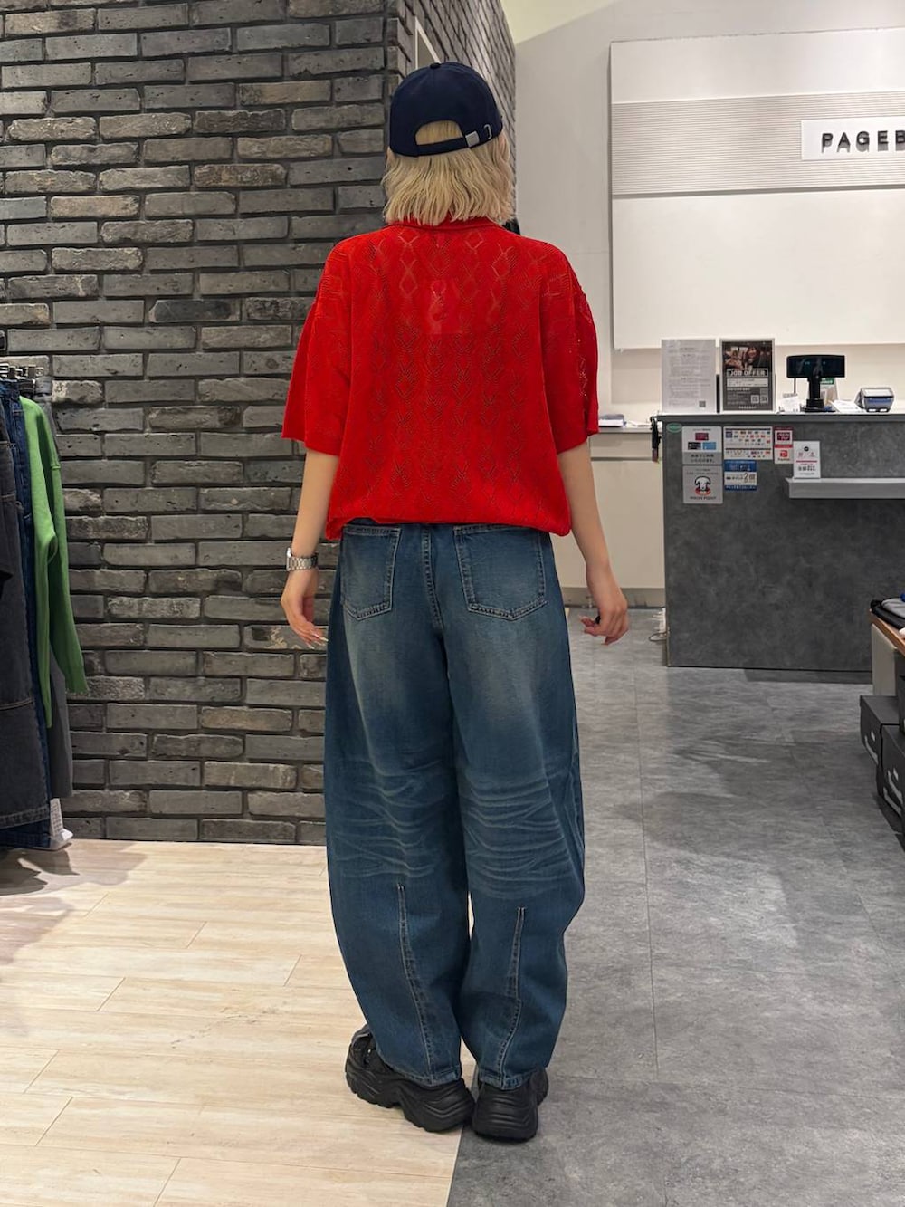 レッド系のポロシャツ、ブラック系のサンダル、ブルー系のデニムパンツを着用したレディースの夏コーディネートの4枚目の写真