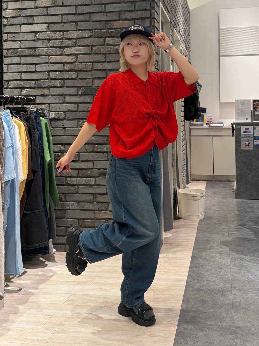 レッド系のポロシャツ、ブラック系のサンダル、ブルー系のデニムパンツを着用したレディースの夏コーディネートの7枚目の写真