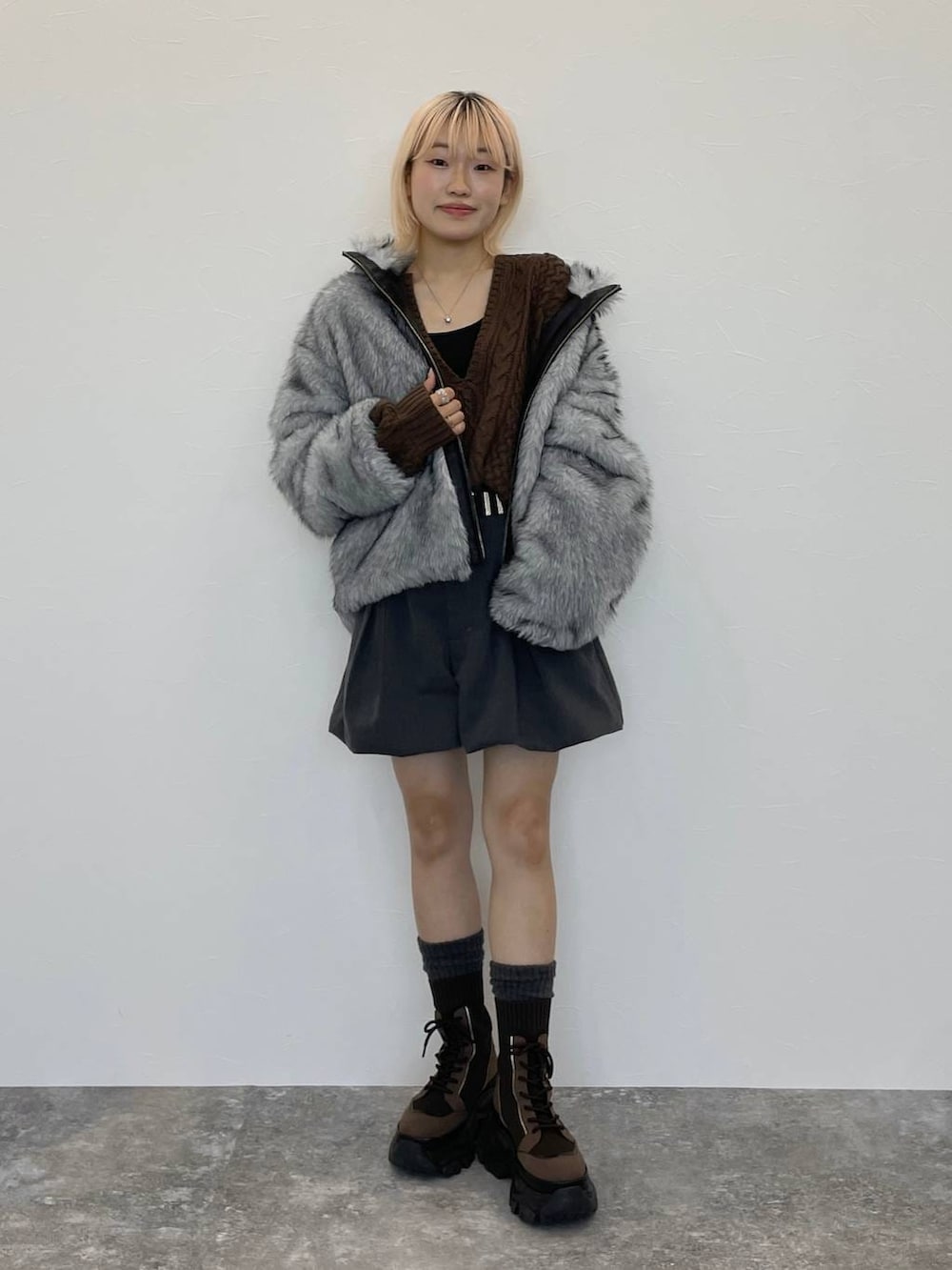 ブラウン系のブーツ、ブラック系のキャミソール、ブラウン系のニット/セーターを着用したレディースの秋コーディネートの2枚目の写真