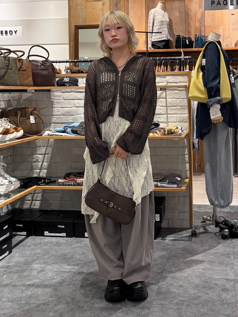 ブラック系のブーツ、ブラウン系のハンドバッグ、ホワイト系のチュニックを着用したレディースの春コーディネートの7枚目の写真