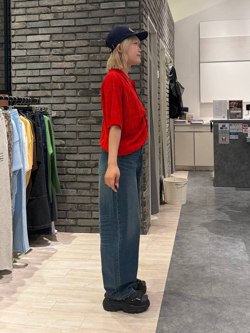 レッド系のポロシャツ、ブラック系のサンダル、ブルー系のデニムパンツを着用したレディースの夏コーディネートの3枚目の写真