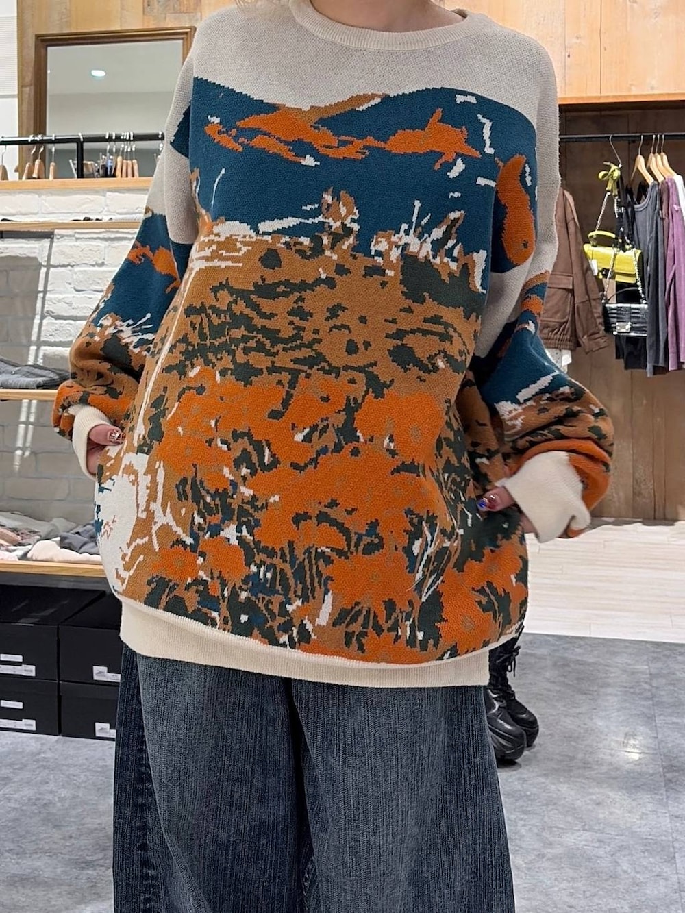 ブラック系のスニーカー、ベージュ系のニット/セーター、ブルー系のデニムパンツを着用したレディースの秋コーディネートの4枚目の写真