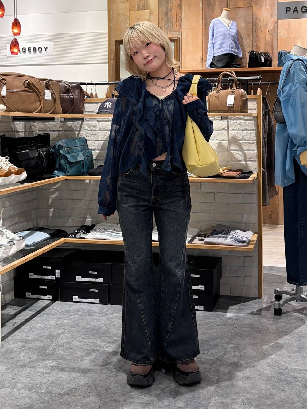 ブラウン系のブーツ、ブルー系のデニムパンツ、イエロー系のトートバッグを着用したレディースの春コーディネートの9枚目の写真