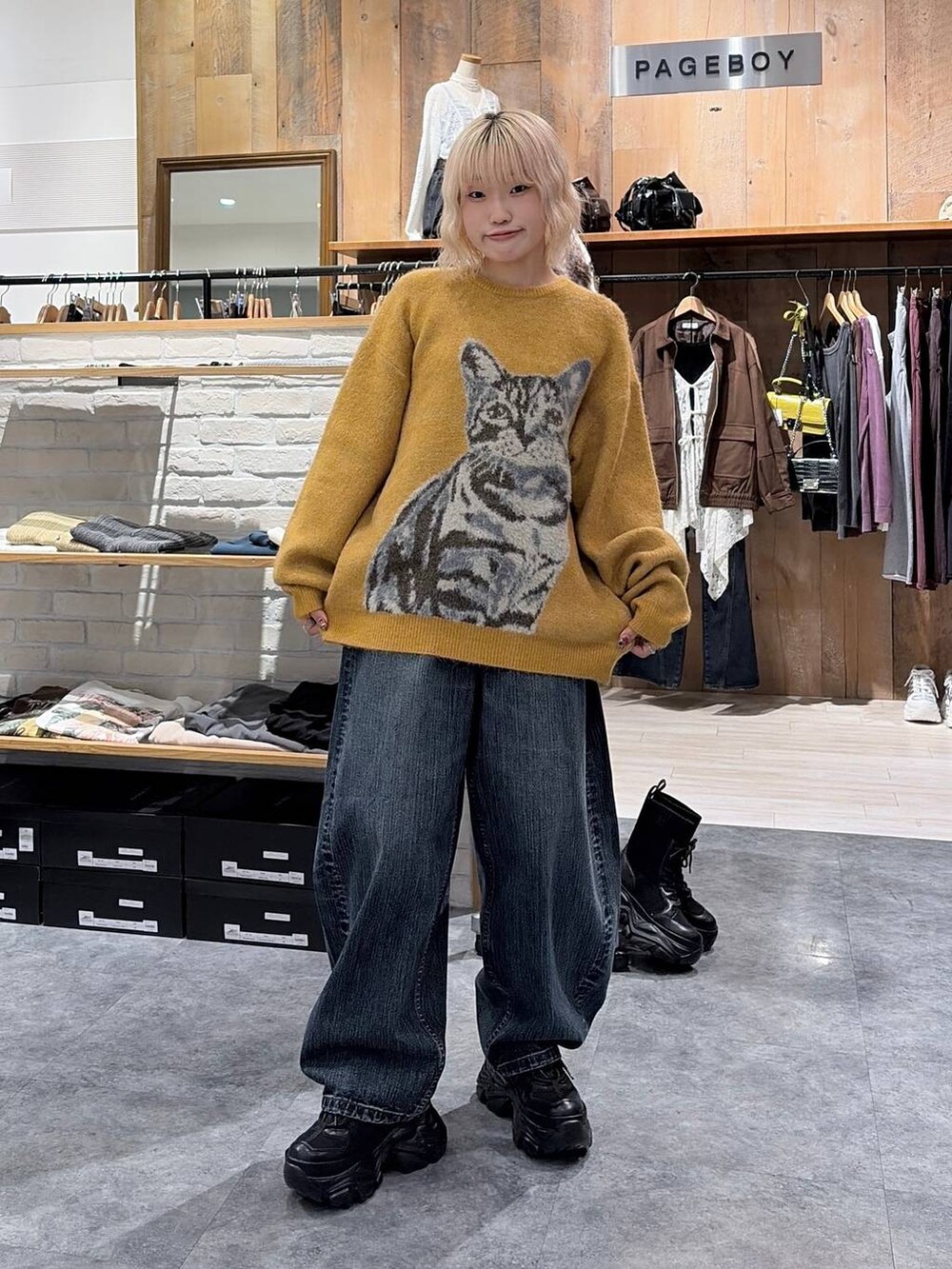 イエロー系のニット/セーター、ブルー系のデニムパンツを着用したレディースの秋コーディネートの2枚目の写真