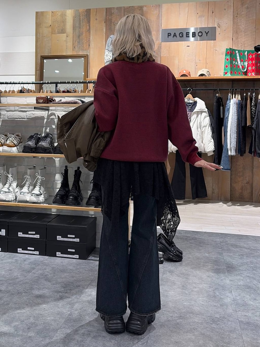 ブラック系のスニーカー、ブルー系のデニムパンツ、ブラック系のチュニックを着用したレディースの冬コーディネートの2枚目の写真