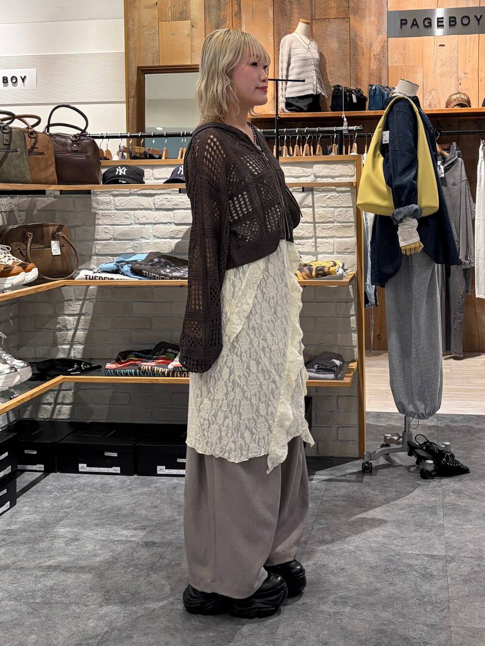 ブラック系のブーツ、ブラウン系のハンドバッグ、ホワイト系のチュニックを着用したレディースの春コーディネートの3枚目の写真