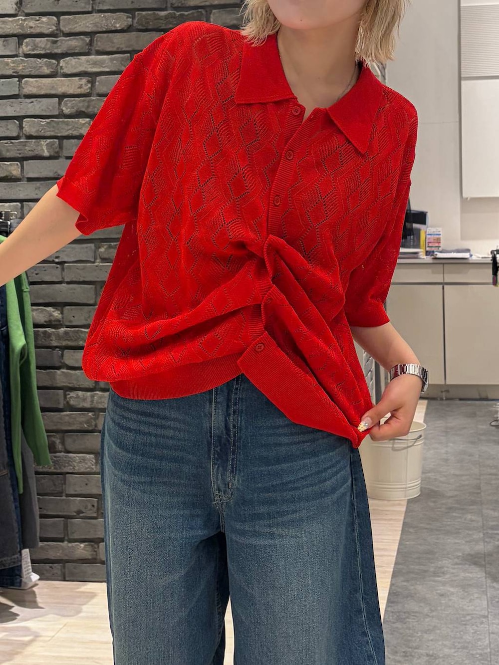 レッド系のポロシャツ、ブラック系のサンダル、ブルー系のデニムパンツを着用したレディースの夏コーディネートの2枚目の写真