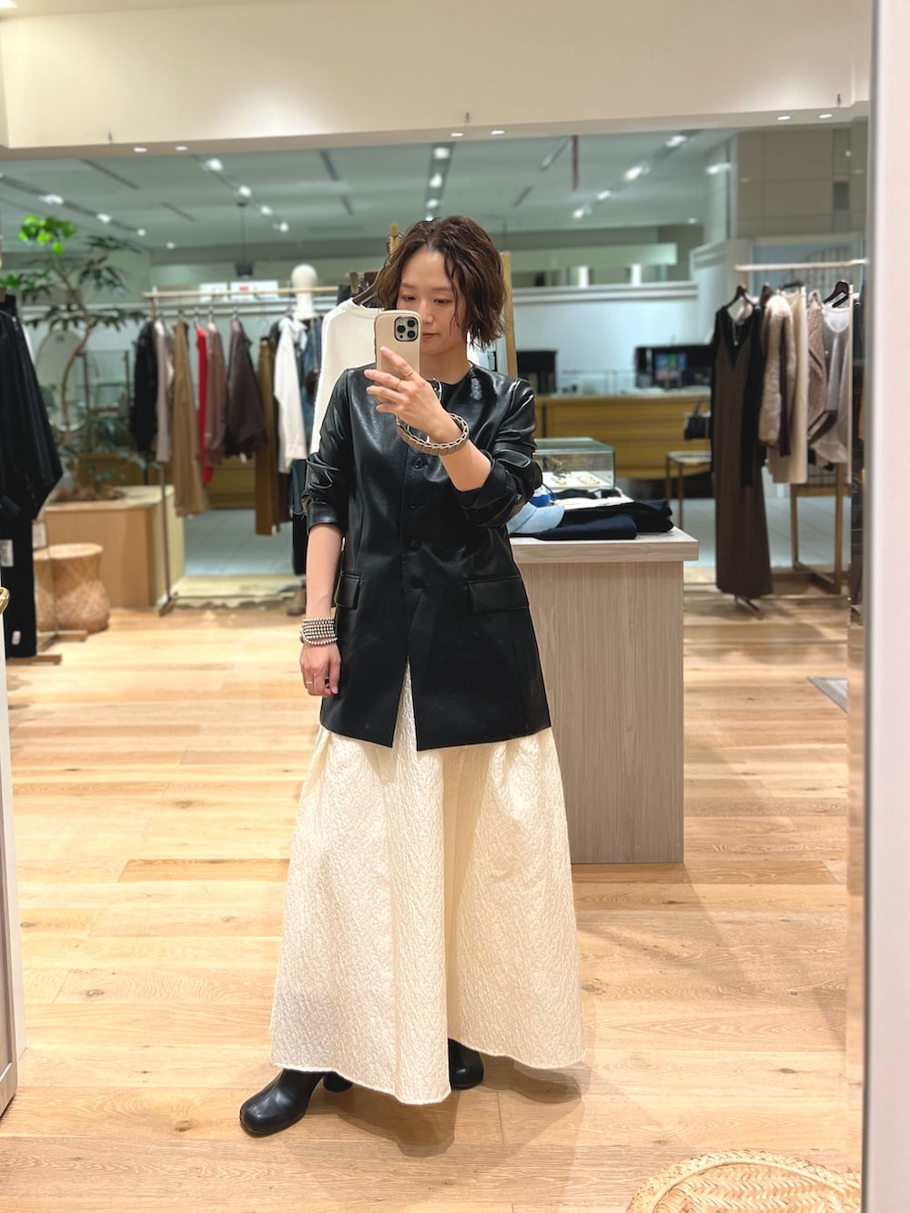 ブラック系のライダースジャケット、ホワイト系のスカート、ブラック系のブーツを着用したレディースの秋コーディネートの3枚目の写真