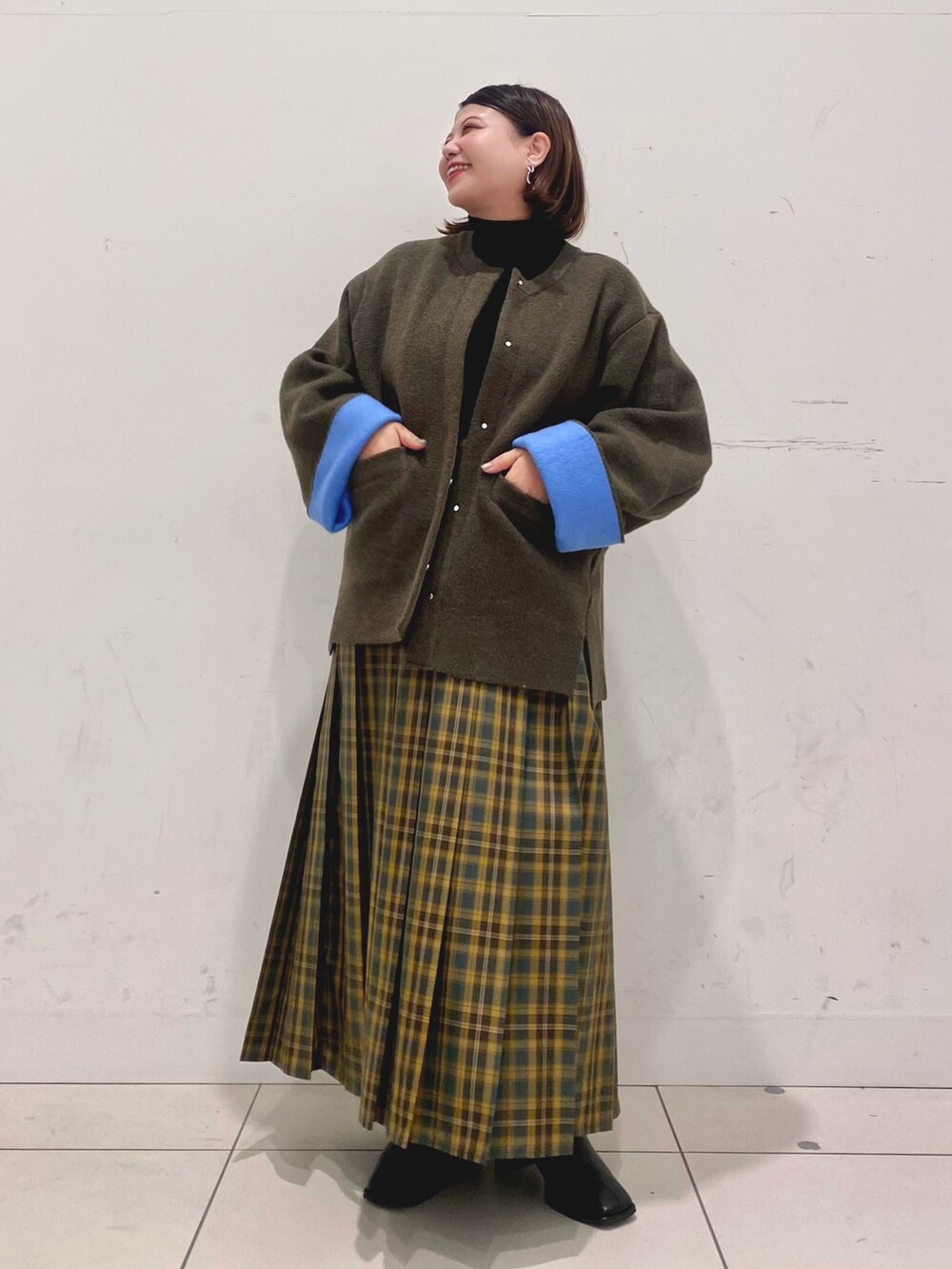 ブラック系のニット/セーター、ブラウン系のその他アウター、イエロー系のスカートを着用したレディースの秋コーディネートの2枚目の写真