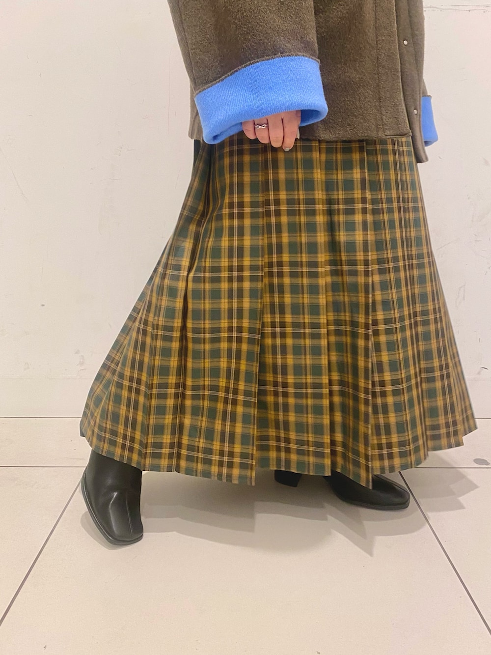 ブラック系のニット/セーター、ブラウン系のその他アウター、イエロー系のスカートを着用したレディースの秋コーディネートの3枚目の写真