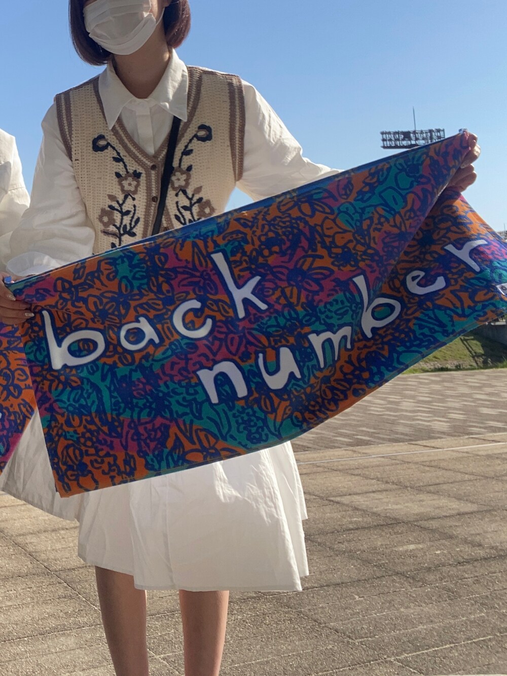 ホワイト系のワンピース、ベージュ系のベスト、ブラック系のショルダーバッグを着用したレディースの春コーディネートの2枚目の写真