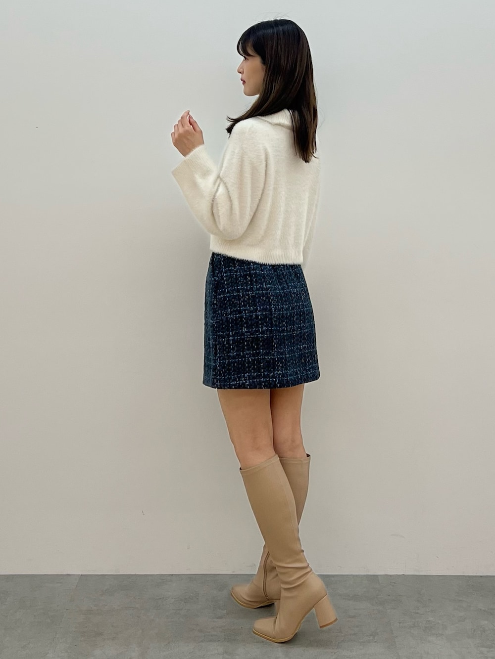 ホワイト系のニット/セーター、ブラック系のスカート、ベージュ系のブーツを着用したレディースの秋コーディネートの3枚目の写真