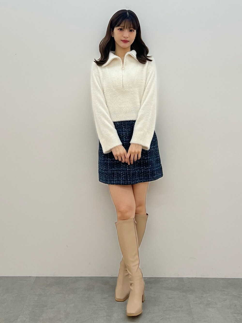 ホワイト系のニット/セーター、ブラック系のスカート、ベージュ系のブーツを着用したレディースの秋コーディネートの2枚目の写真