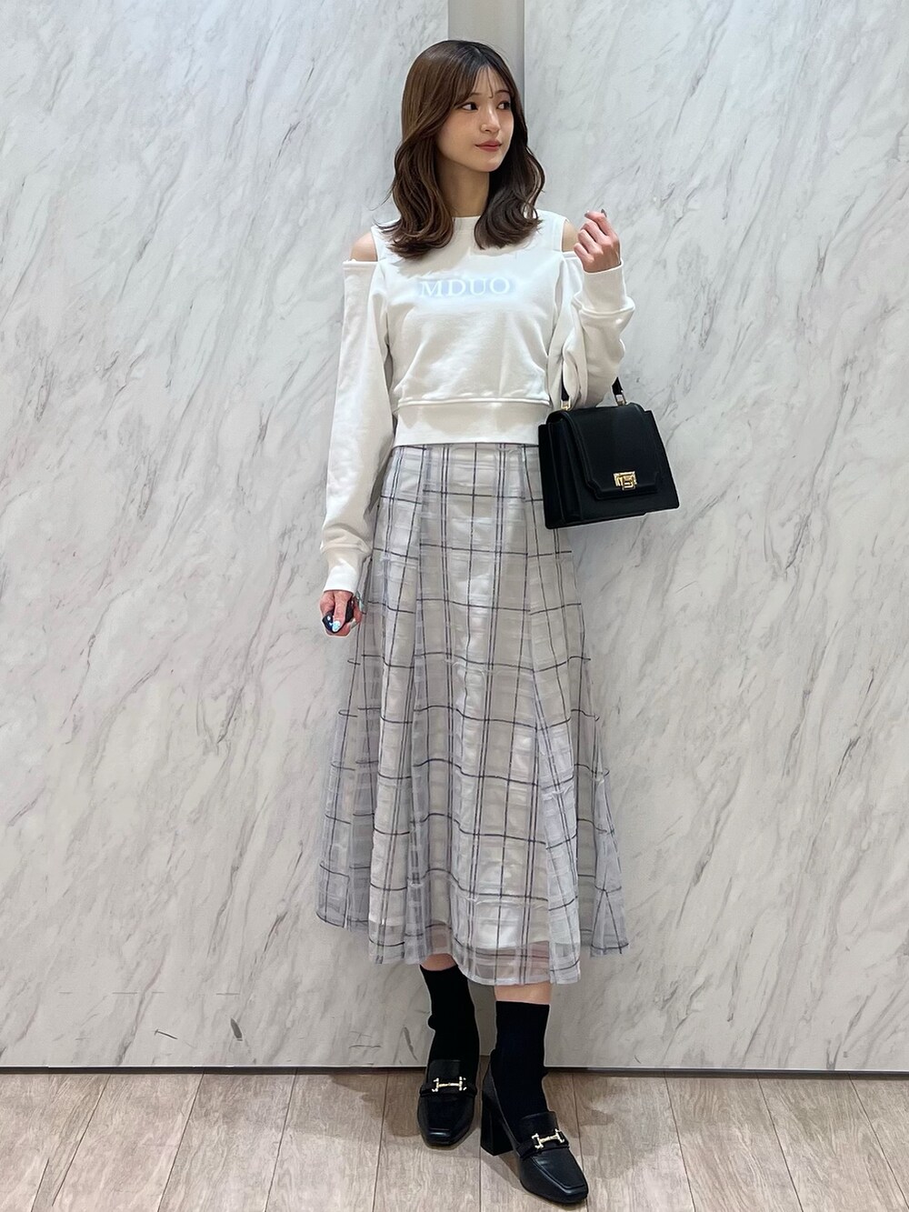 ホワイト系のTシャツ/カットソー、ブルー系のスカート、ブラック系のハンドバッグを着用したレディースの春コーディネートの2枚目の写真