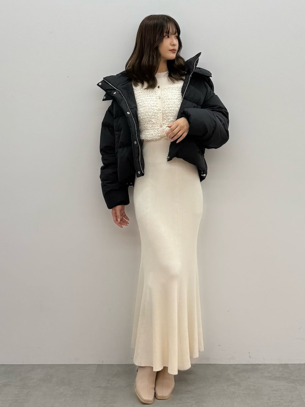 ブラック系のダウンジャケット/コート、ホワイト系のワンピース、ベージュ系のブーツを着用したレディースの秋コーディネートの2枚目の写真