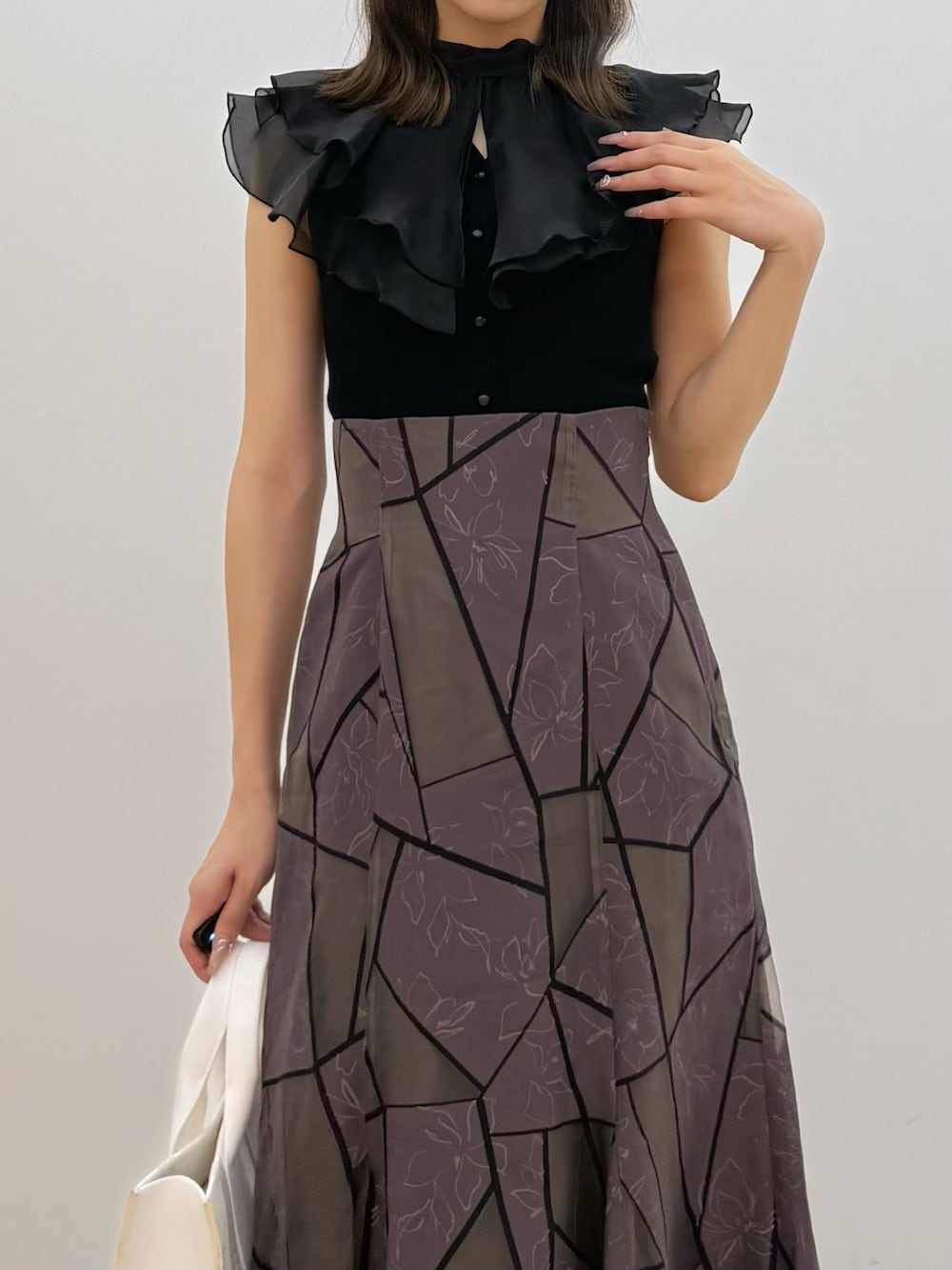 ブラック系のニット/セーター、ブラウン系のスカート、ホワイト系のトートバッグを着用したレディースの夏コーディネートの2枚目の写真