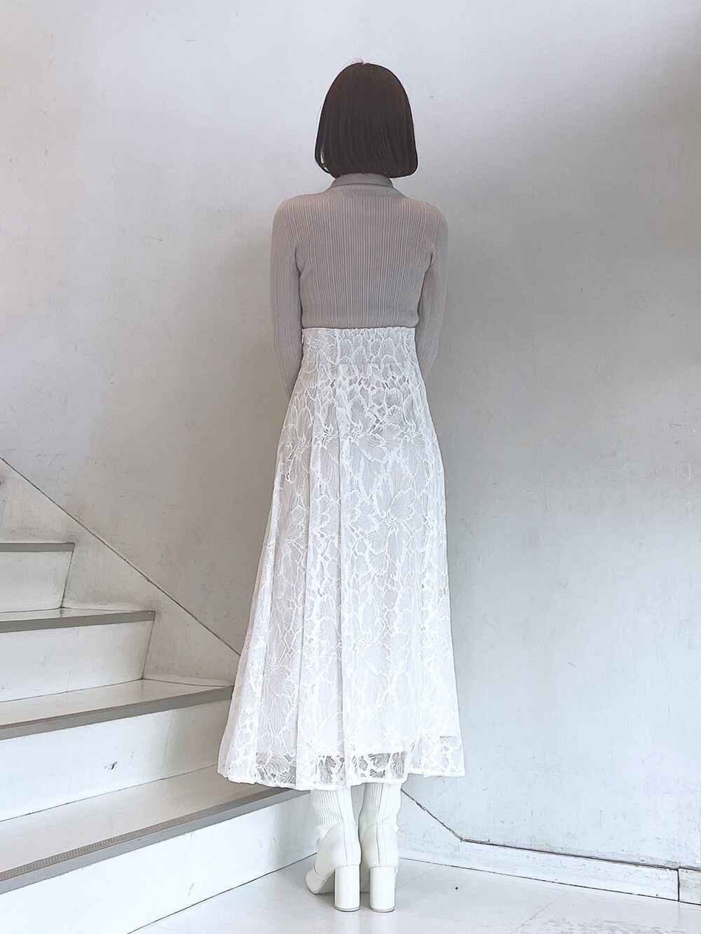 ベージュ系のハンドバッグ、ホワイト系のブーツ、ホワイト系のスカートを着用したレディースの冬コーディネートの4枚目の写真