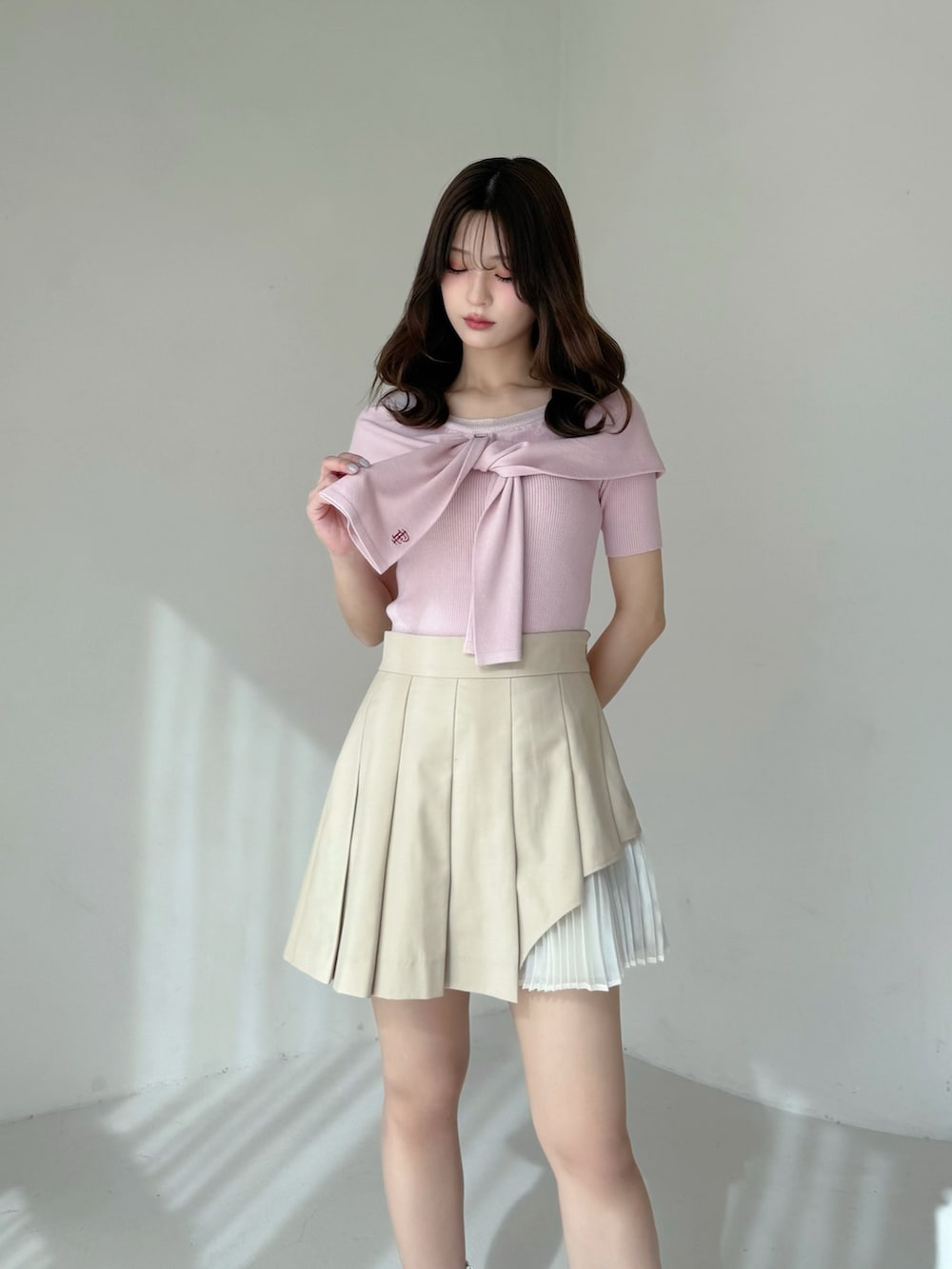 ベージュ系のスカート、ピンク系のニット/セーター、ホワイト系のブーツを着用したレディースの春コーディネートの3枚目の写真