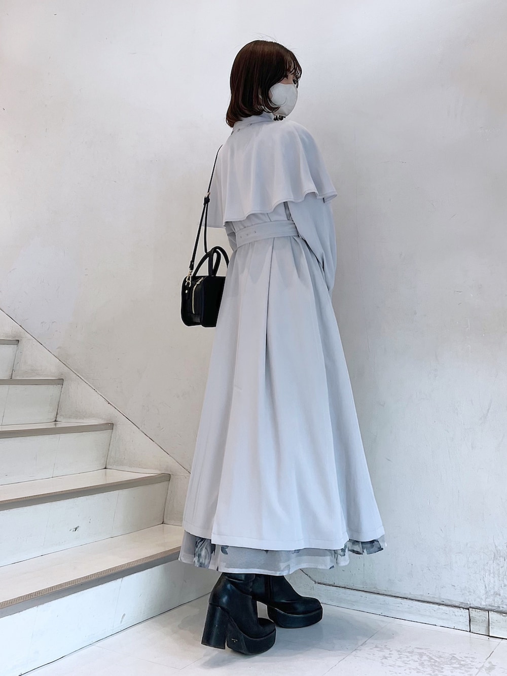 グレー系のトレンチコート、ブラック系のブーツ、ブラック系のハンドバッグを着用したレディースの冬コーディネートの4枚目の写真