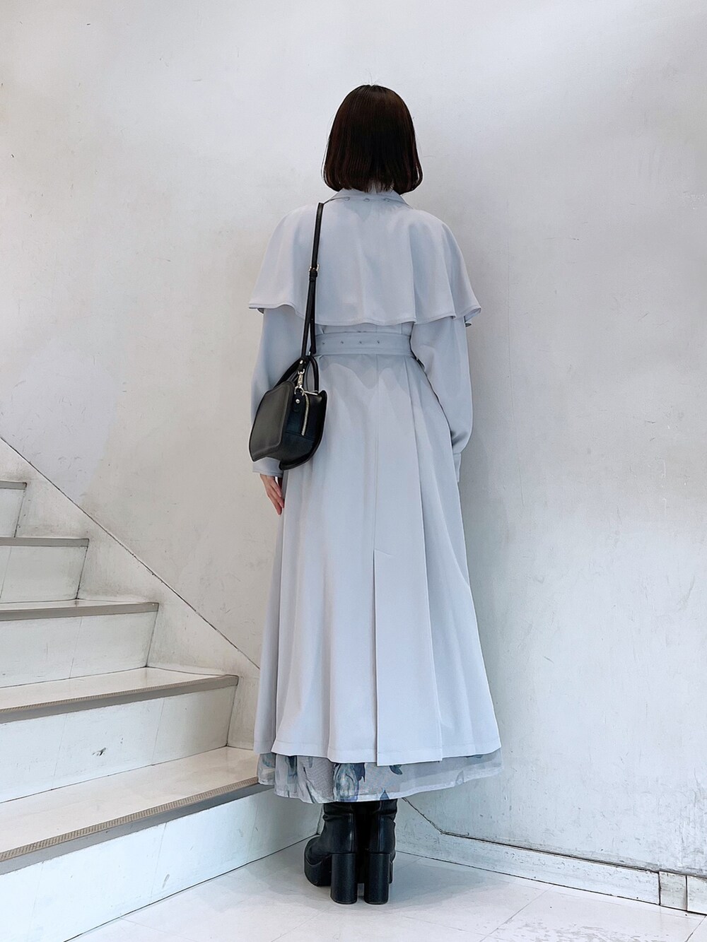 グレー系のトレンチコート、ブラック系のブーツ、ブラック系のハンドバッグを着用したレディースの冬コーディネートの3枚目の写真