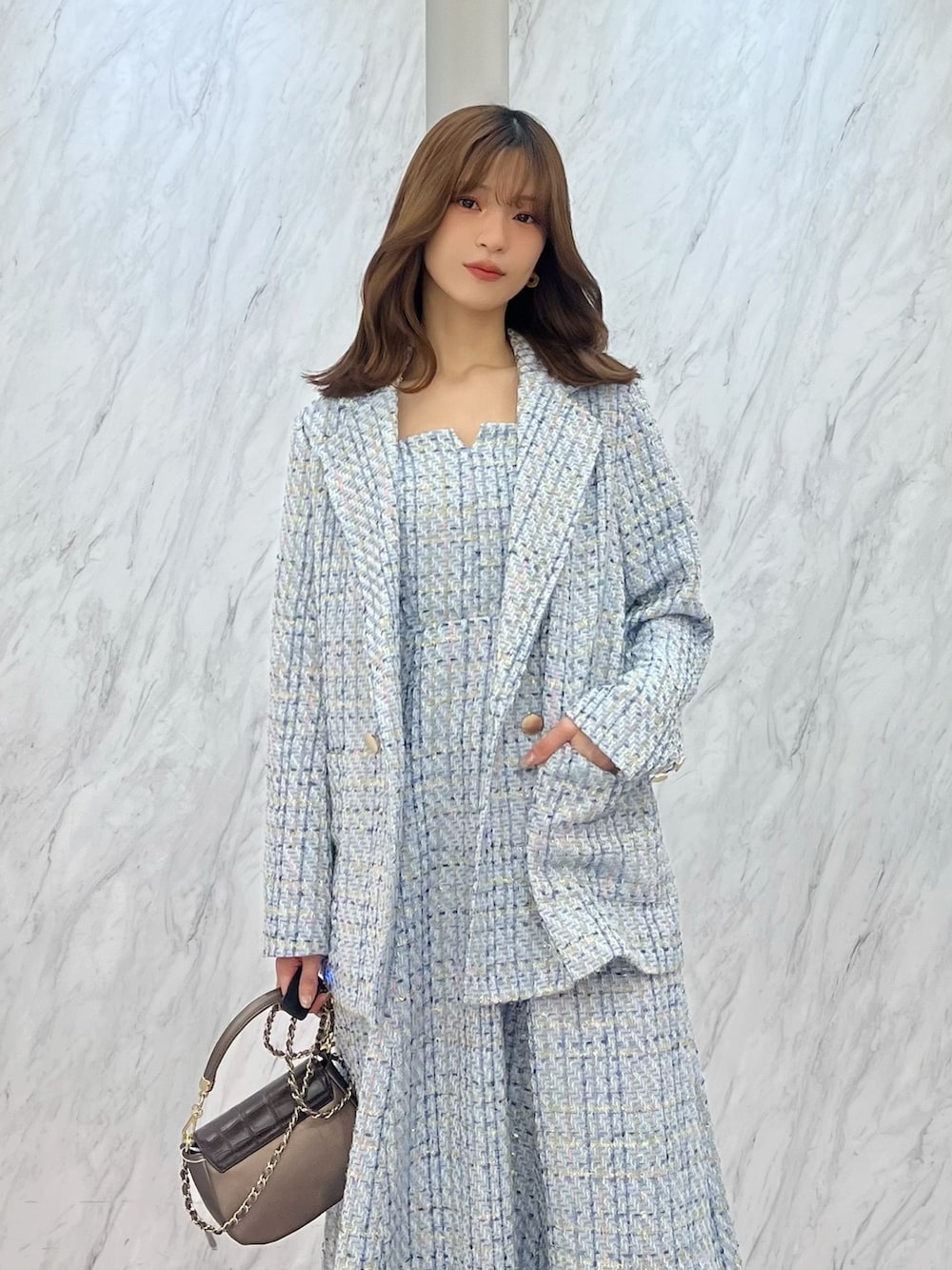 ブルー系のテーラードジャケット、ブルー系のワンピース、ブラウン系のハンドバッグを着用したレディースの冬コーディネートの3枚目の写真