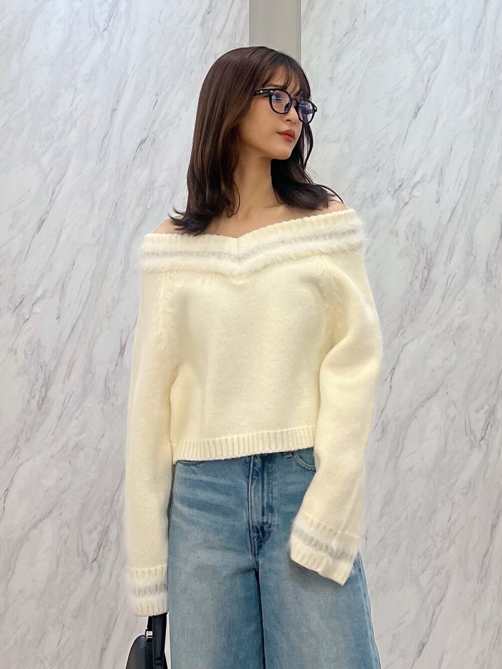 ホワイト系のニット/セーター、ブルー系のデニムパンツ、ブラック系のハンドバッグを着用したレディースの冬コーディネートの5枚目の写真