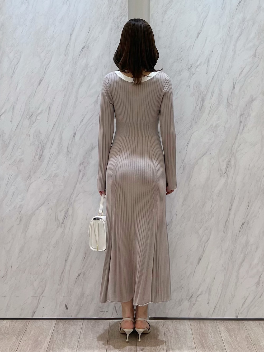 ピンク系のワンピース、ホワイト系のハンドバッグ、ホワイト系のパンプスを着用したレディースの冬コーディネートの4枚目の写真
