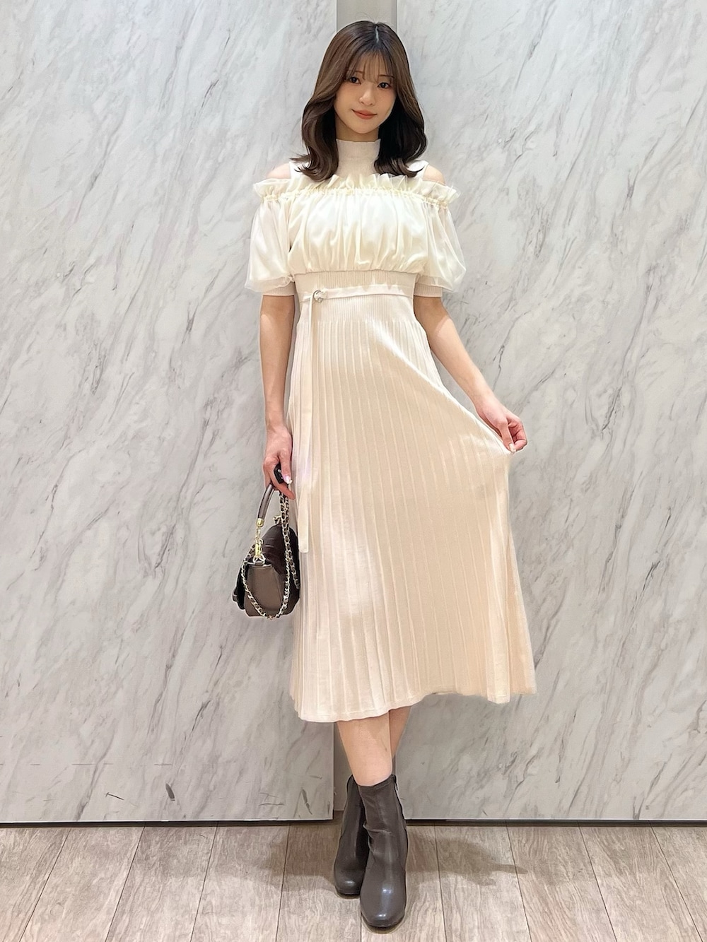 ホワイト系のワンピース、ブラウン系のブーツ、ブラウン系のハンドバッグを着用したレディースの春コーディネートの2枚目の写真