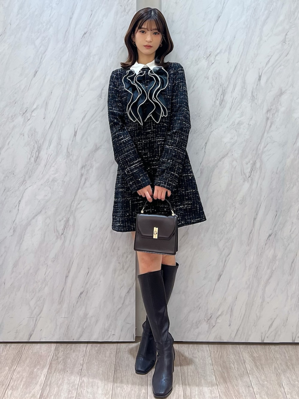 ブラック系のワンピース、ブラウン系のハンドバッグ、ブラウン系のブーツを着用したレディースの秋コーディネートの7枚目の写真