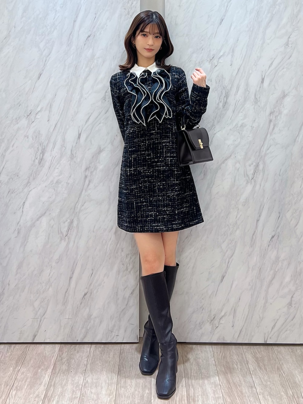 ブラック系のワンピース、ブラウン系のハンドバッグ、ブラウン系のブーツを着用したレディースの秋コーディネートの5枚目の写真