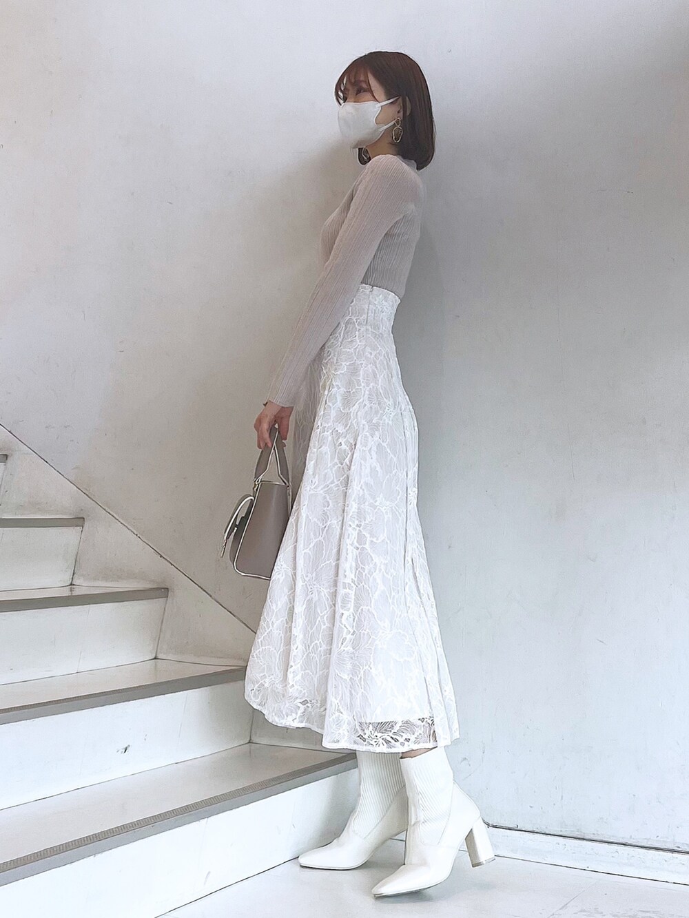 ベージュ系のハンドバッグ、ホワイト系のブーツ、ホワイト系のスカートを着用したレディースの冬コーディネートの3枚目の写真