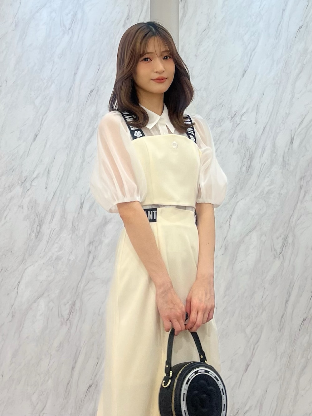 ホワイト系のシャツ/ブラウス、ホワイト系のスカート、ブラック系のショルダーバッグを着用したレディースの冬コーディネートの3枚目の写真