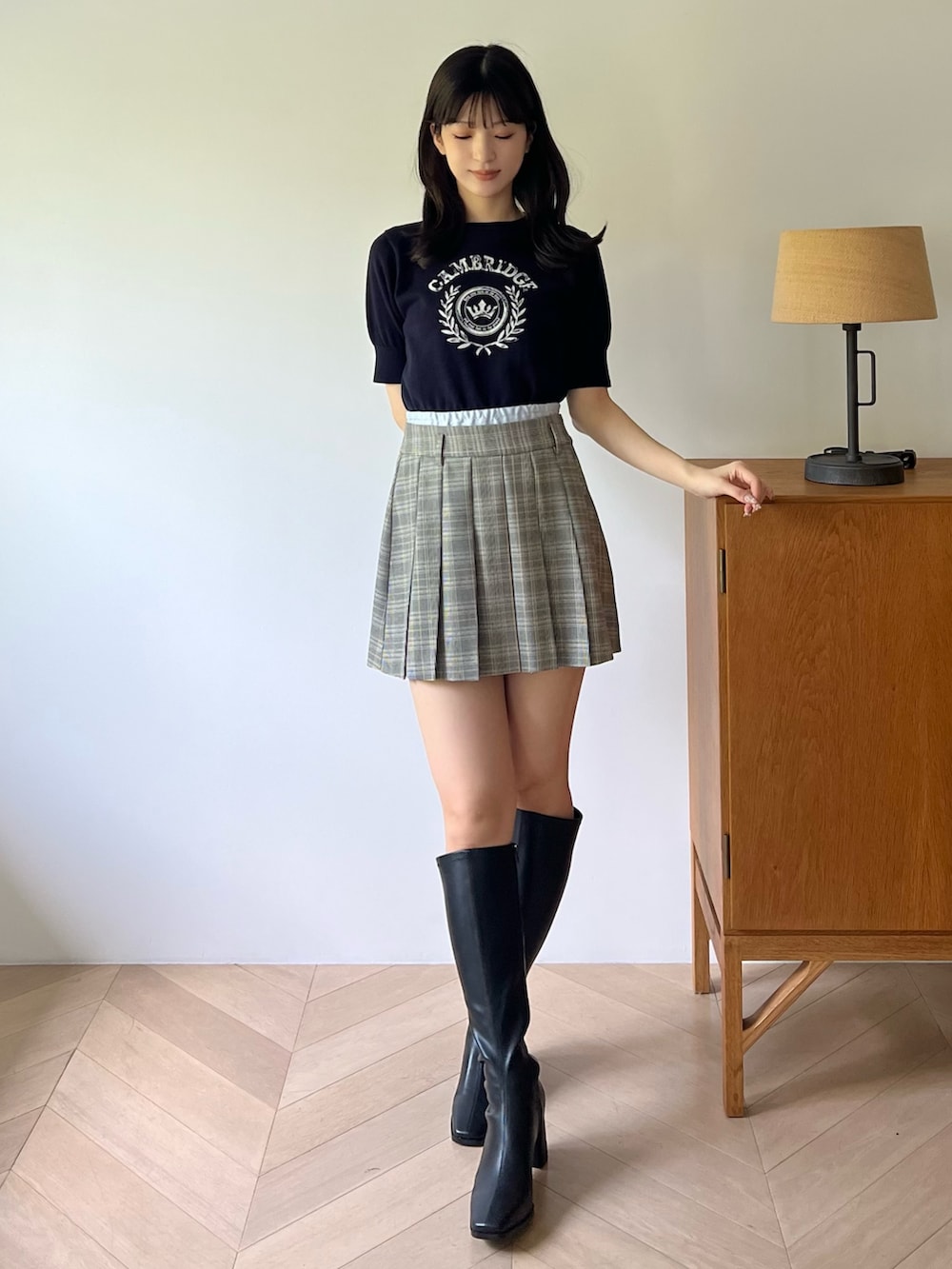 ブルー系のニット/セーター、グレー系のスカート、ブラック系のブーツを着用したレディースの夏コーディネートの7枚目の写真