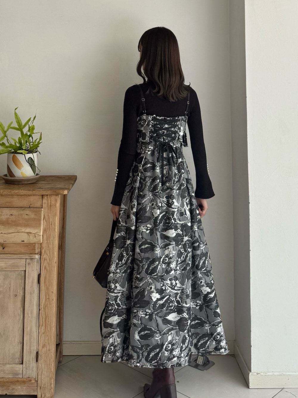 ブラック系のニット/セーター、ブラック系のワンピース、レッド系のブーツを着用したレディースの秋コーディネートの3枚目の写真