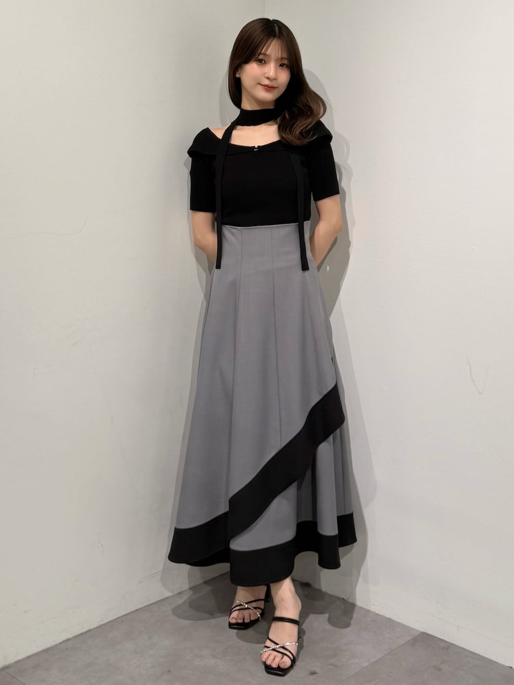 ブラック系のニット/セーター、グレー系のスカート、ブラック系のサンダルを着用したレディースの春コーディネートの2枚目の写真